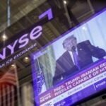 Wall Street trading floor with market data screens showing a downturn amidst Middle East conflict.