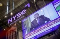 Wall Street trading floor with market data screens showing a downturn amidst Middle East conflict.