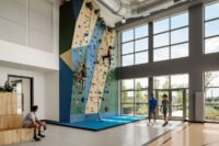 Exterior view of Steel House in Denver's RiNo Arts District, showcasing its C-channel metal facade and steel-framed entrance tower against a natural backdrop.