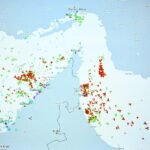 A cargo ship navigating the narrow Strait of Hormuz, with a backdrop of a distant coastline, symbolizing the high-stakes journey through a critical global waterway.