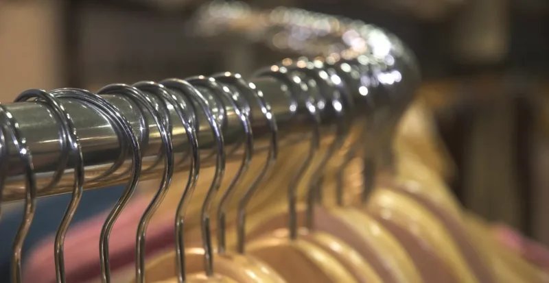 L'Énigme des Tailles de Vêtements : Pourquoi le 38 d'une Marque n'est Pas le 38 d'une Autre ? 3 Une femme, visiblement perplexe, essayant un jean dans une cabine d'essayage, avec plusieurs autres vêtements de différentes tailles et marques autour d'elle, symbolisant la confusion des tailles non standardisées.