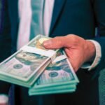 A panoramic view of the Wall Street financial district in New York City with skyscrapers and a bustling street scene, symbolizing record-breaking bonuses.
