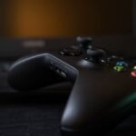 A Windows 11 PC screen displaying the Xbox gaming interface with a controller nearby