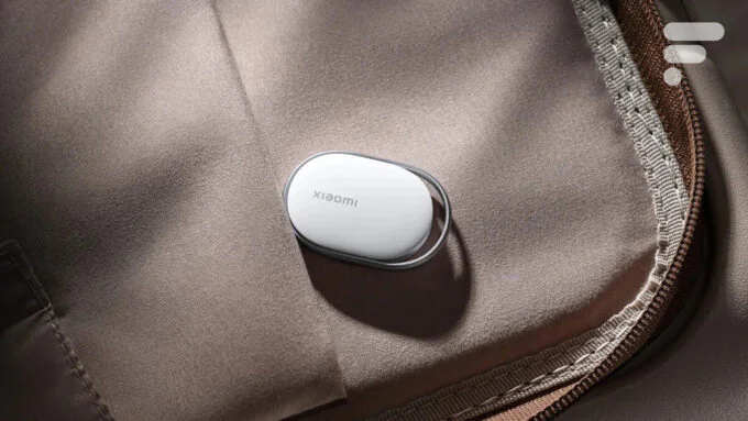 Le Xiaomi Tag, un petit traqueur d'objets noir avec un trou pour porte-clés, posé sur une surface claire.
