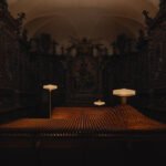 A mesmerizing view of Aesop's 'Factory of Light' installation in Milan, featuring Aposē lamps illuminating a landscape of recycled fragrance vials within a historic church.