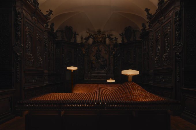 A mesmerizing view of Aesop's 'Factory of Light' installation in Milan, featuring Aposē lamps illuminating a landscape of recycled fragrance vials within a historic church.