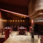 Interior view of TABRA restaurant by Andreea Cornila, showcasing the burgundy color scheme, skylight, and chrome bar.