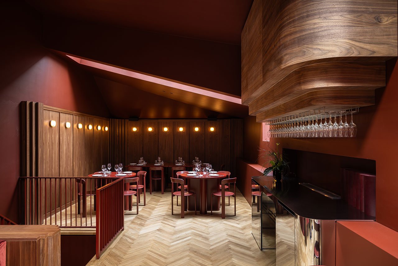 Interior view of TABRA restaurant by Andreea Cornila, showcasing the burgundy color scheme, skylight, and chrome bar.