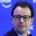 A stylized graphic representing AI technology, possibly with network lines and a subtle government or security agency emblem in the background.