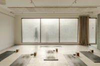 Interior view of Basic Space yoga studio reception area with frosted glass blocks, sculptural check-in desk, and natural light.