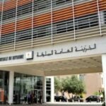 Pompe à essence affichant des prix élevés, avec des billets de banque en arrière-plan, symbolisant l'impact de la hausse des carburants sur les finances publiques et le pouvoir d'achat.