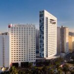 Vue extérieure de l'hôtel Sofitel Casablanca Tour Blanche, un gratte-ciel moderne et élégant, situé au cœur du quartier historique de Casablanca, sous un ciel clair.