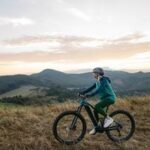 A person riding an electric bicycle on a paved path, with a blurred background of nature.