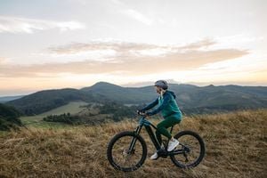 A person riding an electric bicycle on a paved path, with a blurred background of nature.