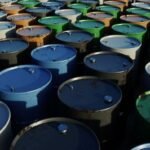 صورة توضيحية لبراميل نفط أو سفينة شحن في مضيق مائي يرمز لمضيق هرمز، تعكس التوترات الجيوسياسية.