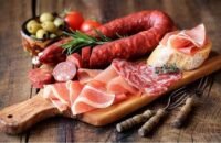 صورة لمجموعة من الأطعمة الشائعة مثل الحلويات واللحوم المصنعة والعصائر، مع إشارة تحذيرية.