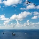 صورة توضيحية للتوتر بين الولايات المتحدة وإيران، ربما سفن حربية أو خريطة المنطقة أو علمي البلدين.