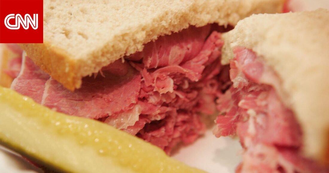 صورة مقربة لشرائح لحم مصنعة مثل السلامي والنقانق، توضح جاذبيتها الظاهرية مع تلميحات لخطرها الصحي.