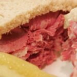 صورة مقربة لشرائح لحم مصنعة مثل السلامي والنقانق، توضح جاذبيتها الظاهرية مع تلميحات لخطرها الصحي.