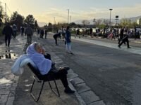 عضو في قوات الأمن الإيرانية يراقب حركة المرور أمام لوحة إعلانية كبيرة في ساحة انقلاب بطهران، تحمل عبارة "مضيق هرمز سيبقى مغلقاً" باللغة الفارسية، بتاريخ 5 أبريل 2026.