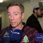 صورة للمدربين الدميعي وسانتوس وهما يتحدثان بعد مباراة كرة قدم.