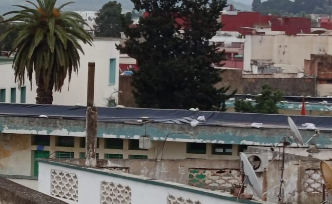 صورة تظهر أقسامًا مدرسية مغطاة بالبلاستيك في وزان، مع تلاميذ يدرسون في ظروف صعبة.