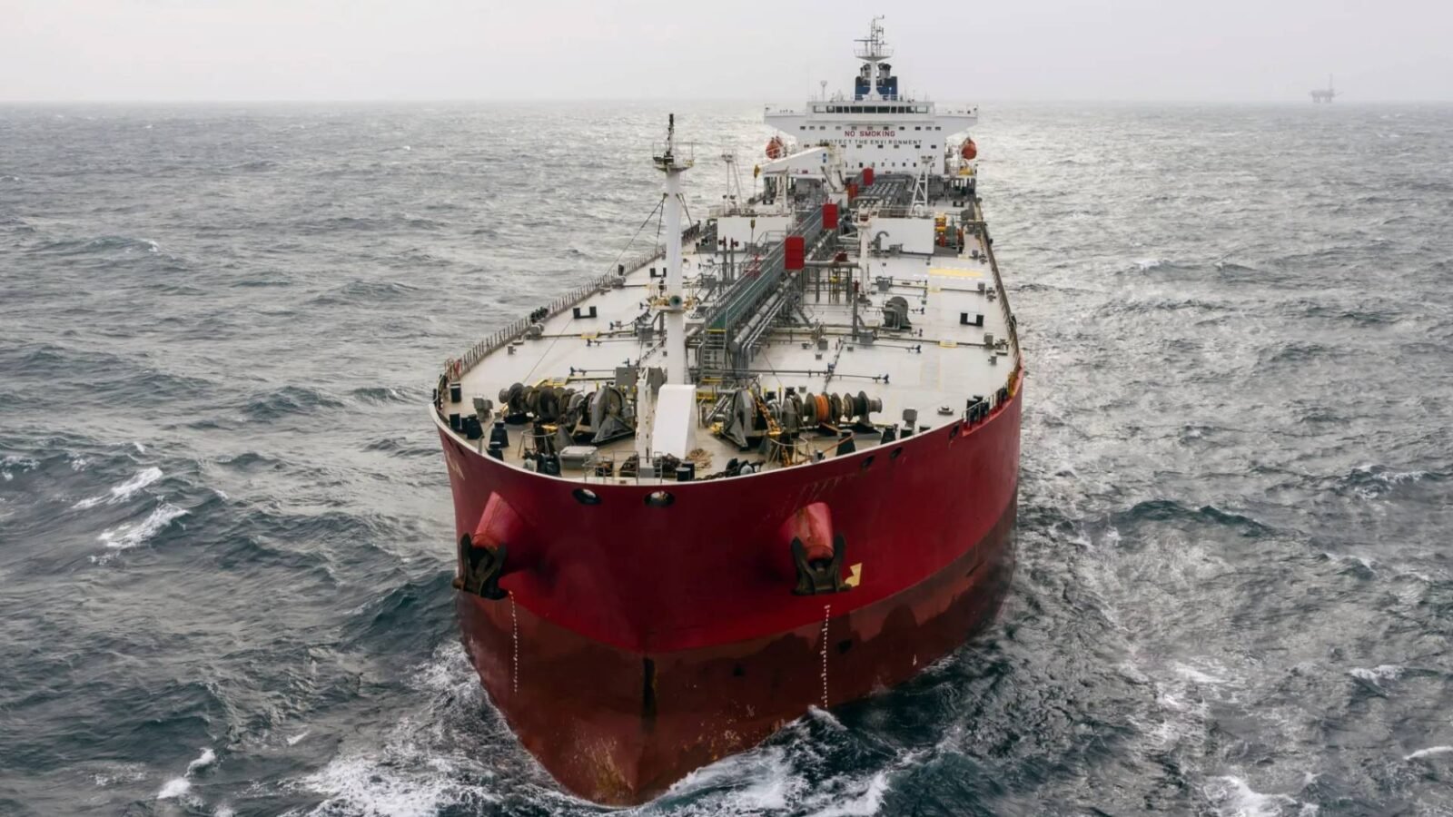 صورة لناقلة نفط ضخمة تعبر مضيق هرمز، مع خلفية لمياه الخليج والسواحل الجبلية.