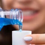 صورة توضيحية لزجاجة غسول فم بجانب قلب بشري، ترمز للعلاقة بين صحة الفم والقلب.