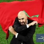 صورة للمدرب وليد الركراكي وهو يرتدي بدلة تدريب ويقف على أرضية ملعب كرة قدم.