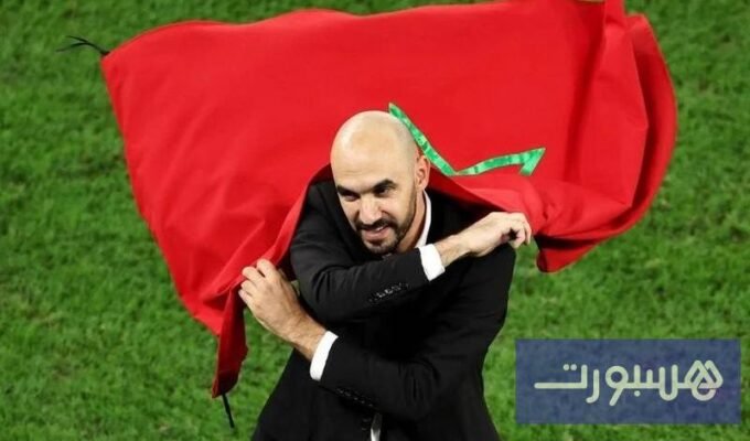 صورة للمدرب وليد الركراكي وهو يرتدي بدلة تدريب ويقف على أرضية ملعب كرة قدم.