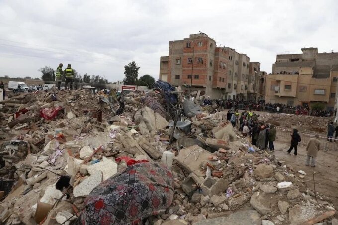 Image d'un immeuble effondré à Fès, avec des débris et des équipes de secours.