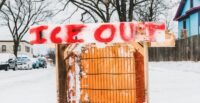 An anti-ICE sign displayed prominently outside a house in a Minneapolis neighborhood, symbolizing local opposition to immigration enforcement.