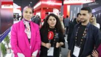 Des visiteurs du GITEX interagissant avec des innovations technologiques sur un stand d'exposition animé.