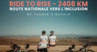 Deux cyclistes, dont Aziza Gannoune, devant un paysage marocain, symbolisant leur parcours de 2408 km pour l'inclusion des personnes handicapées.