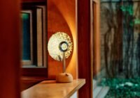 The Juba TL-1 Lamp in 'Heaven' colorway, a light-pink conch shell hue, emitting a soft, ethereal glow on a surface.