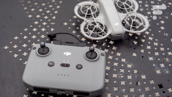 Un drone DJI Neo blanc avec ses accessoires (casque FPV, télécommande, batteries) posés sur une surface sombre, avec un fond flou.