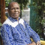 Portrait de l'écrivain guinéen Tierno Monénembo, l'air pensif, avec un arrière-plan flou.