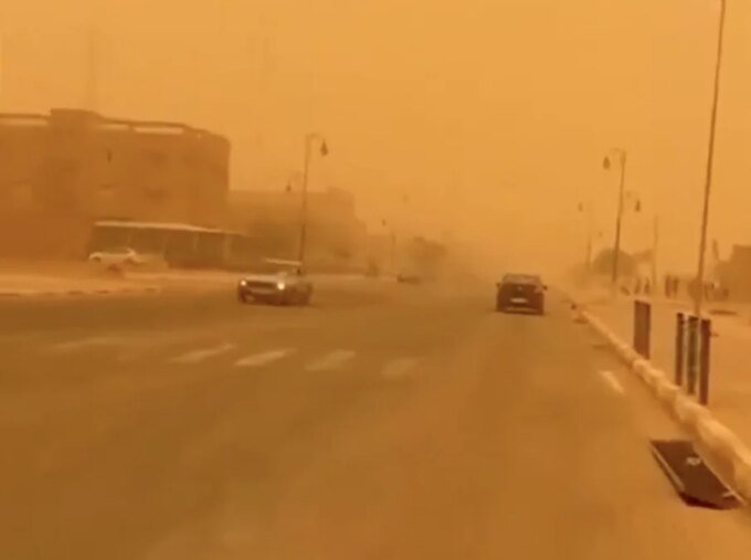 Une tempête de sable balayant le sud du Maroc, réduisant la visibilité sous un ciel orangé.