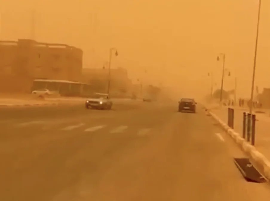 Une tempête de sable balayant le sud du Maroc, réduisant la visibilité sous un ciel orangé.