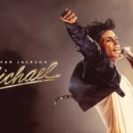 Jaafar Jackson dans le rôle de Michael Jackson, recréant une pose emblématique sur scène, avec un éclairage dramatique et une foule en arrière-plan.