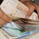 Une main tendue avec des dirhams marocains, symbolisant la prédominance du cash dans les transactions quotidiennes au Maroc, avec un smartphone en arrière-plan représentant le défi de la digitalisation.