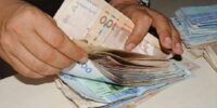 Une main tendue avec des dirhams marocains, symbolisant la prédominance du cash dans les transactions quotidiennes au Maroc, avec un smartphone en arrière-plan représentant le défi de la digitalisation.