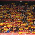 Des supporters dans un stade de football, avec une ambiance tendue ou des bannières. L'image doit évoquer la foule et le contexte sportif.