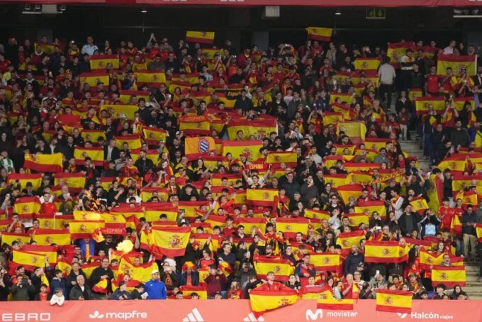 Des supporters dans un stade de football, avec une ambiance tendue ou des bannières. L'image doit évoquer la foule et le contexte sportif.