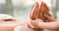 Une personne recevant une séance de réflexologie plantaire, les pieds étant massés avec soin, symbolisant la détente et le bien-être.