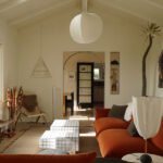 A vibrant living room in a Silver Lake bungalow featuring a burnt orange velvet sofa, chrome accents, and eclectic decor, showcasing a blend of vintage and modern design.