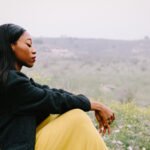 A person sitting alone by a serene lake, reflecting on the natural surroundings, symbolizing peace and connection to nature.