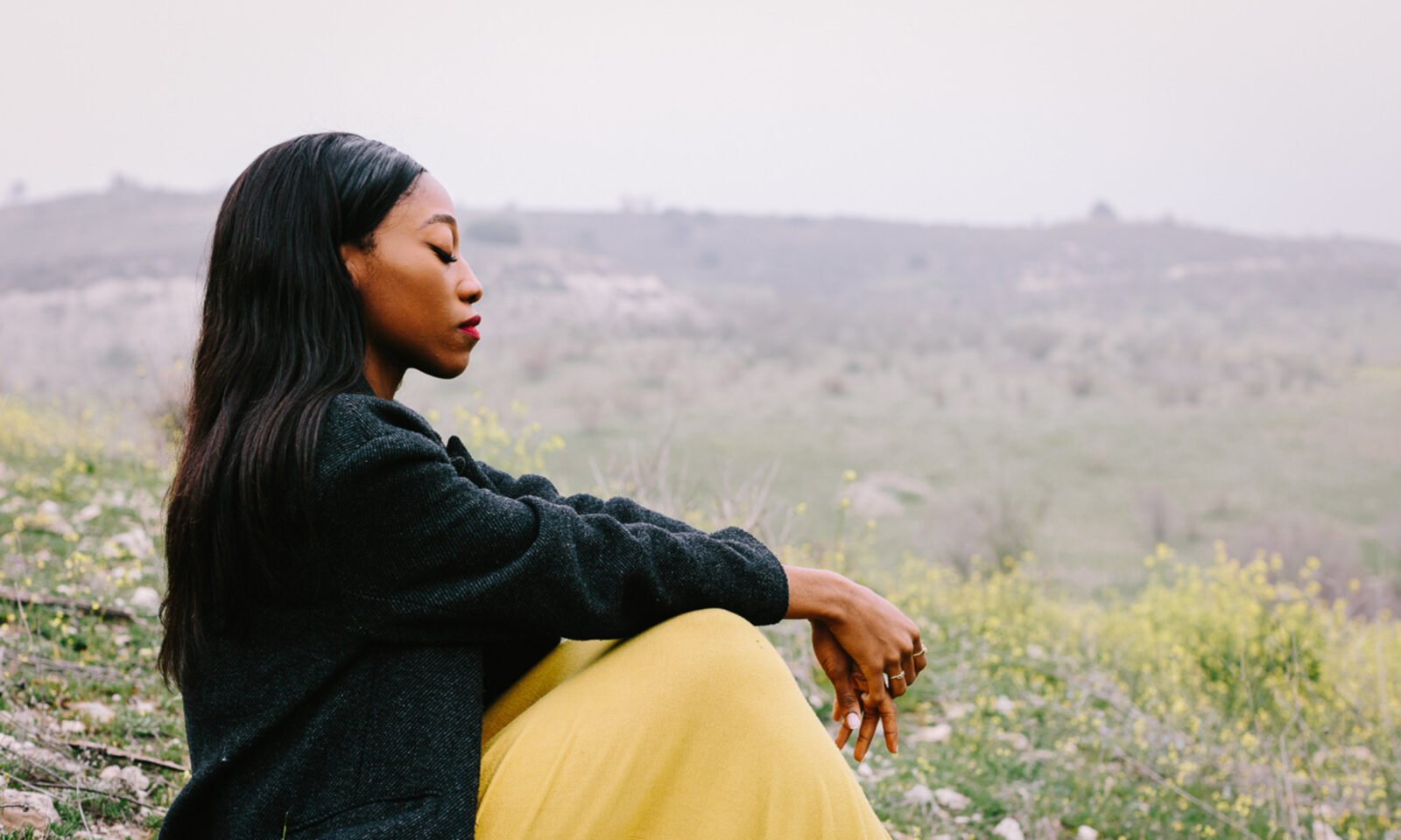 A person sitting alone by a serene lake, reflecting on the natural surroundings, symbolizing peace and connection to nature.