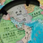 China Slams U.S. Strait of Hormuz Blockade as 'Dangerous and Irresponsible' 6 A large oil tanker navigating the narrow Strait of Hormuz, with a naval vessel in the background, symbolizing geopolitical tensions and critical trade routes.