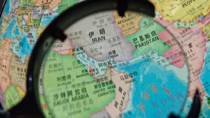 China Slams U.S. Strait of Hormuz Blockade as 'Dangerous and Irresponsible' 9 A large oil tanker navigating the narrow Strait of Hormuz, with a naval vessel in the background, symbolizing geopolitical tensions and critical trade routes.